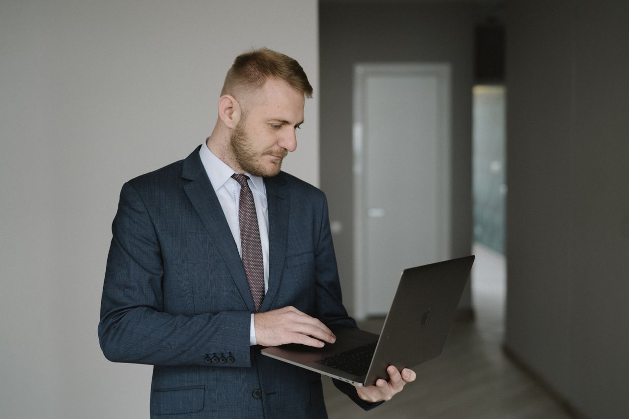 Businessman in suit works on laptop in a modern office setting, conveying professionalism.