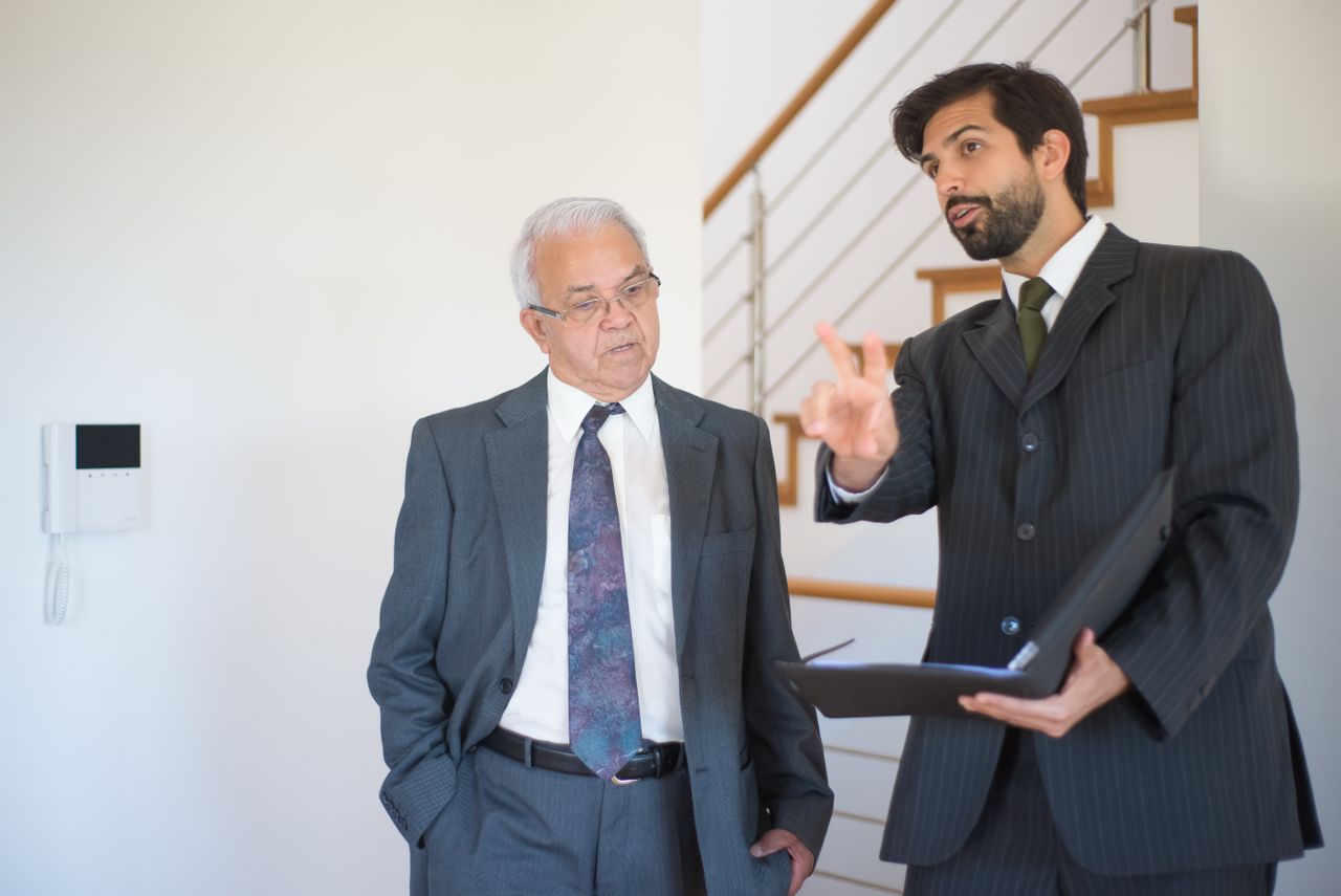 Real estate agent explaining property details to a client indoors.